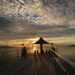 石垣島「フサキビーチ」桟橋で夕日を眺めるカップル　